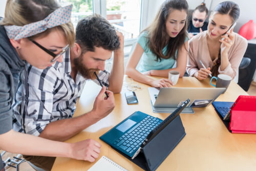 Side view of a dedicated self-employed young man analyzing a difficult task while working in a modern hub for digital nomads or independent contractors