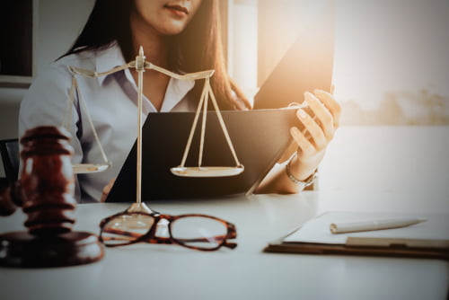 business woman and lawyers discussing contract papers with brass scale on wooden desk in office